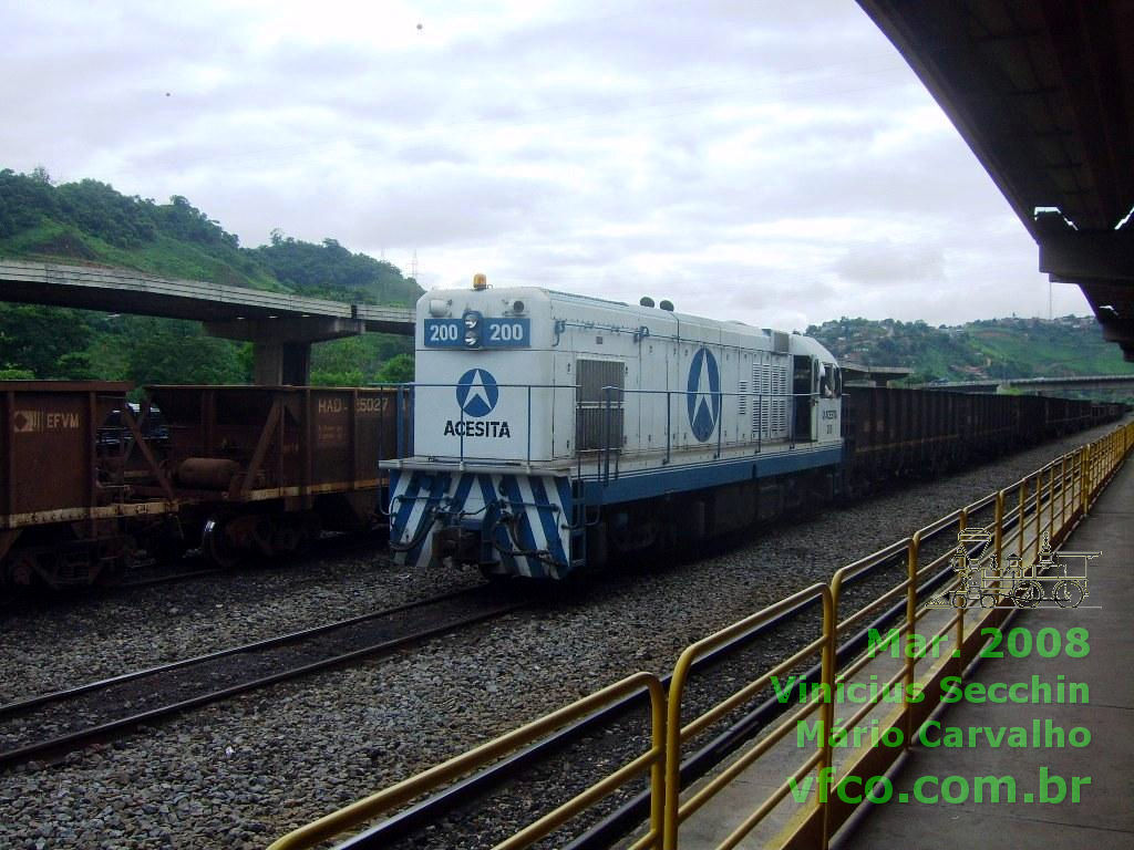 Foto da locomotiva G12 n&ordm; 200 da Acesita tracionando vag&otilde;es g&ocirc;ndola na esta&ccedil;&atilde;o de M&aacute;rio Carvalho, Tim&oacute;teo, Minas Gerais