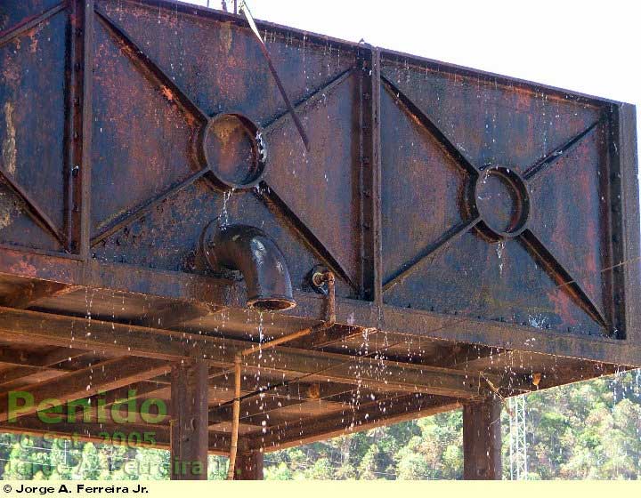 Detalhe da caixa d'água da estação ferroviária de Penido, com reforços aparentemente de lâminas soldadas, e a saída para o tubo de abastecimento das locomotivas a vapor