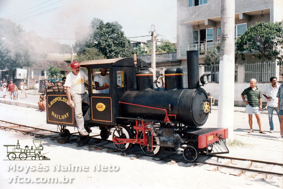 O ferreomodelista conduzindo sua locomotiva a "vapor vivo" sobre os trilhos armados em uma praça