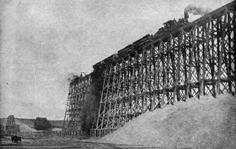 Enorme viaduto ferroviário em cavaletes de madeira, utilizado para efetuar um longo trecho de aterro ferroviário